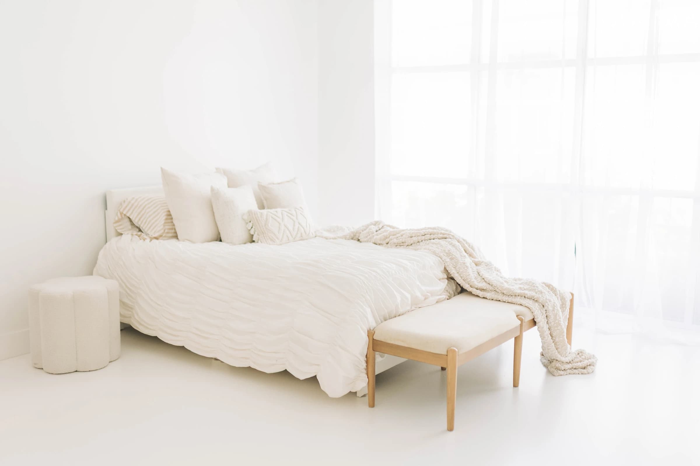Studio A: window light falling across the styled bed and white-painted floors