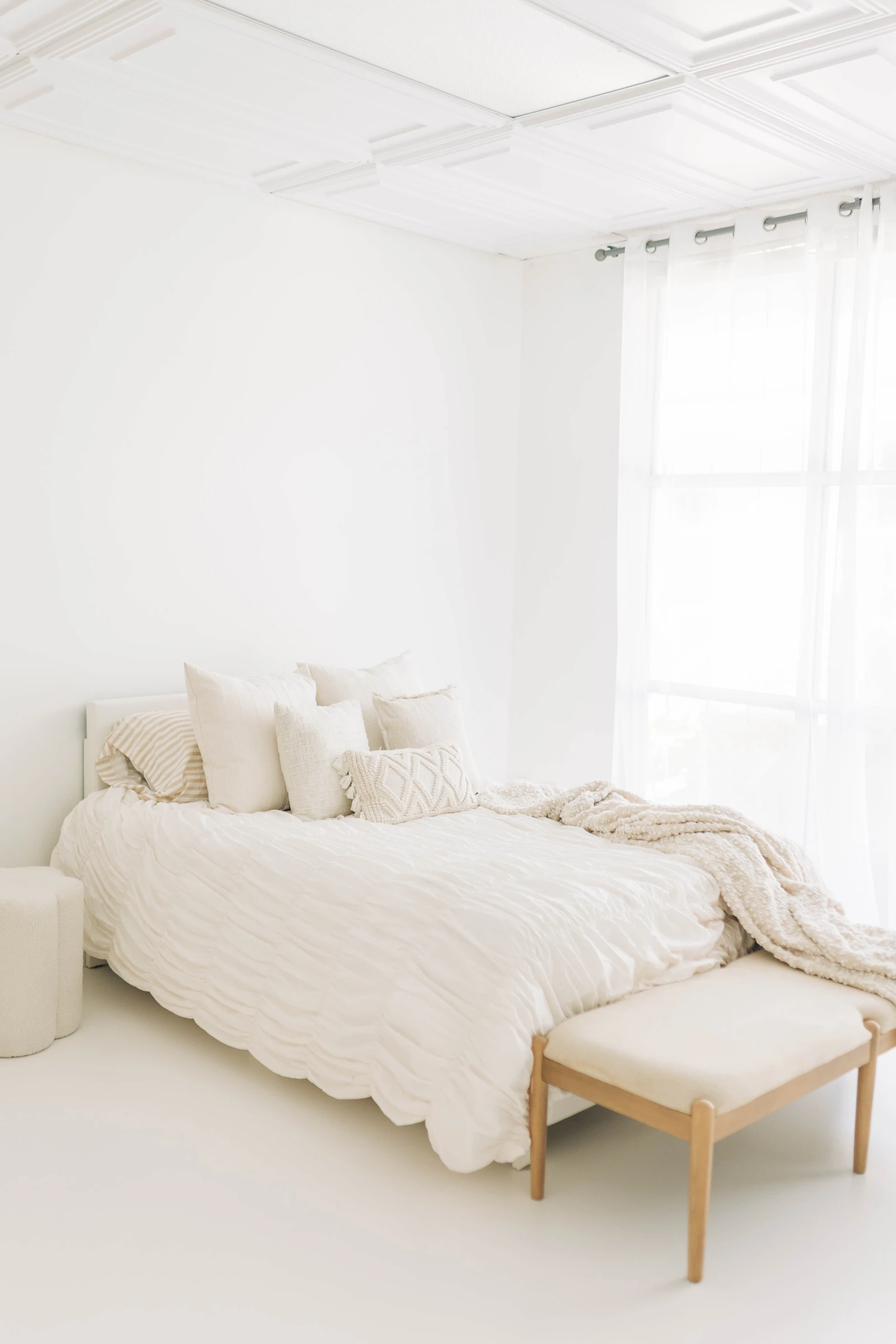 A softly styled full-size bed in flattering window light, ready for a boudoir session