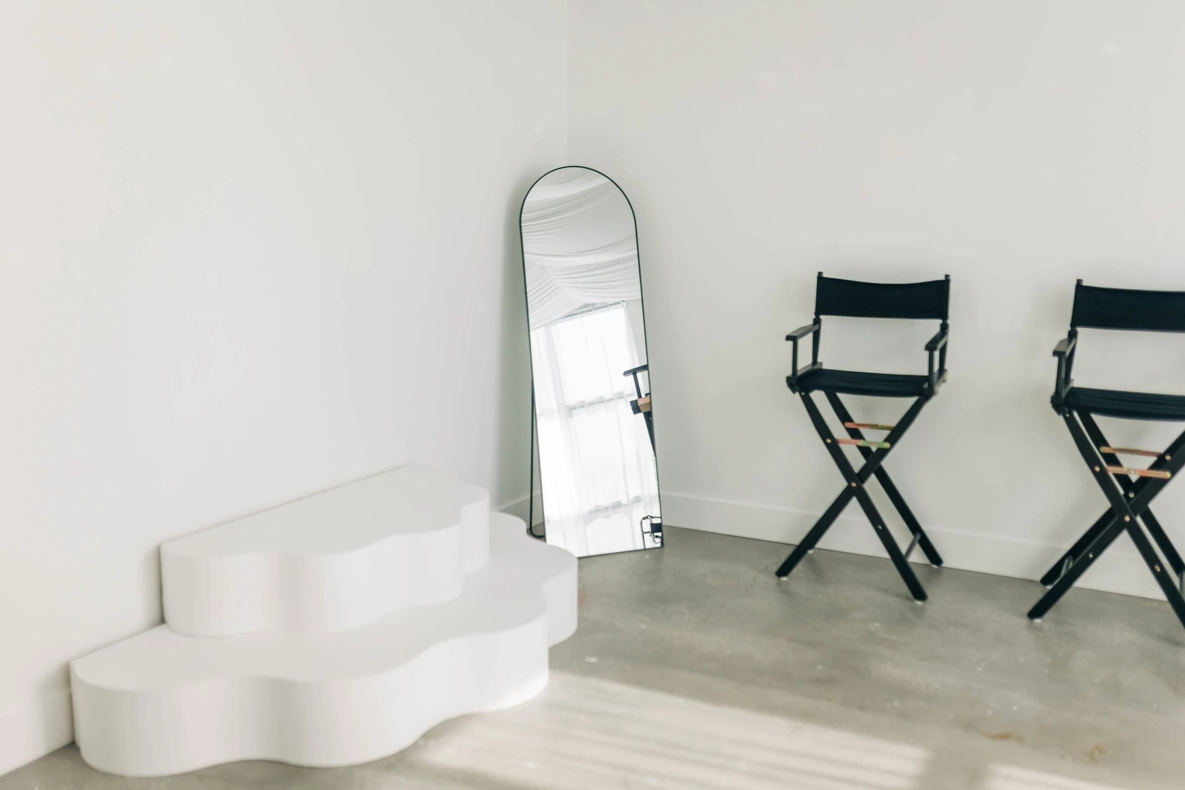 The wavy white stage steps and arched mirror beside Studio B's director's chairs